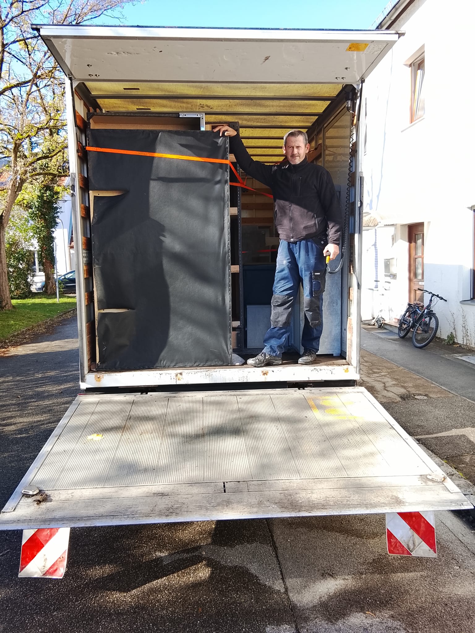 Umzugstransporter wird beladen, Möbel mit Gurten gesichert